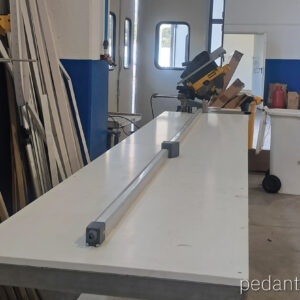 Sistema automático de tope medidor Pedante integrado en una línea de sierra ingletadora en un taller en Italia