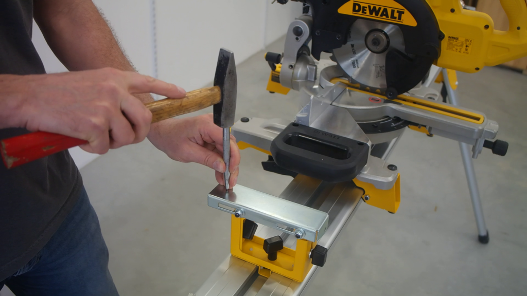 DeWALT DE7024 work support bracket being prepared with a center punch for drilling mounting holes.