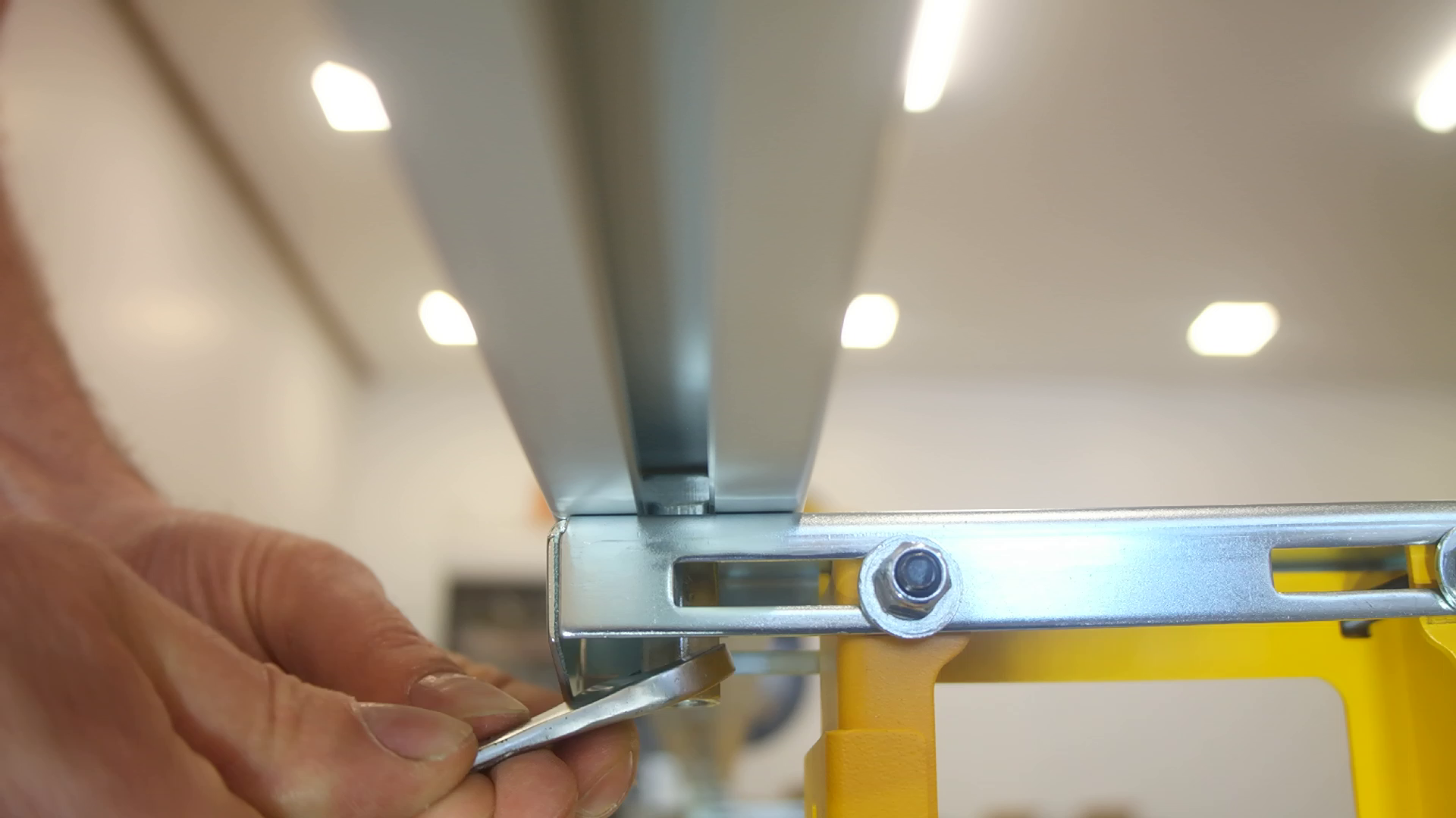 An extended nut being tightened with a wrench on a T-head bolt inserted in the bottom of a Pedante Digital Miter Saw Fence.