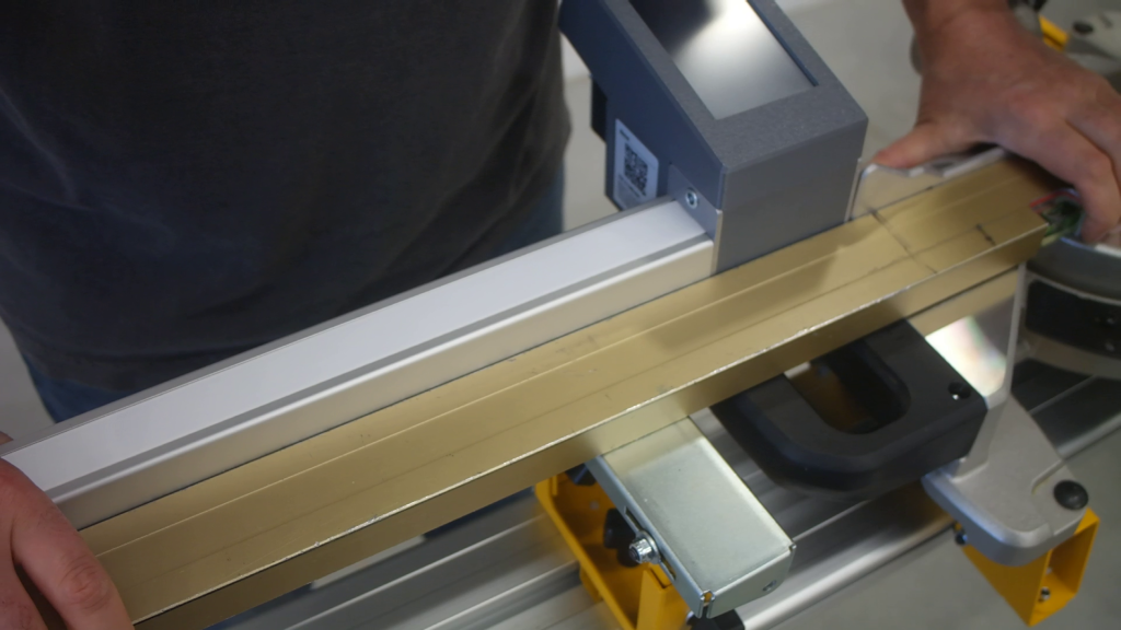 Pedante Automated Length Stop mounted on a portable miter saw stand, being aligned with the saw fence.