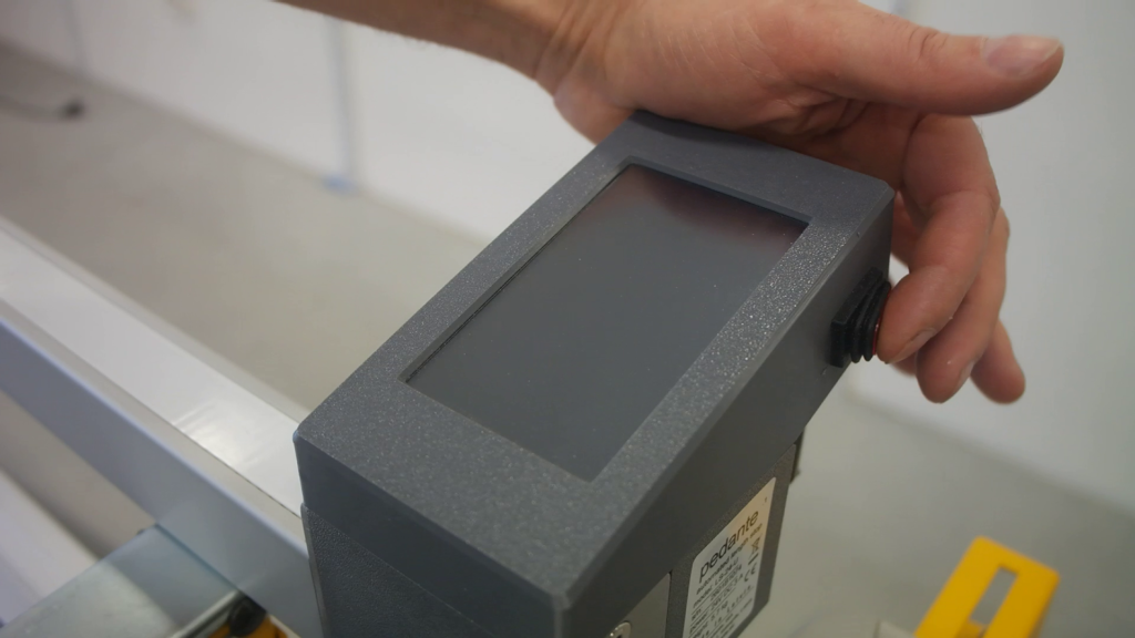 The "ON" button being pressed on a Pedante Automated Length Stop's control unit.